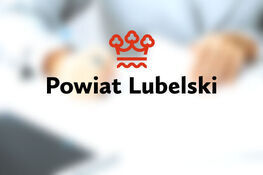 Logo Powiatu Lubelskiego na rozmazanym tle