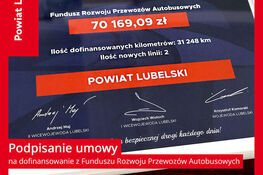 Na zdjęciu znajduje się tablica z informacją o dofinansowaniu w wysokości 70 169,09 zł na rzecz Powiatu Lubelskiego na rozwój przewozów autobusowych. Widoczne są imiona i nazwiska urzędników.