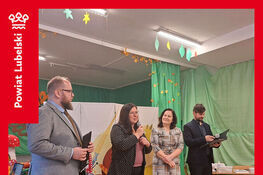 Grupa osób na scenie podczas wydarzenia.  W tle dekoracje z motywem jesiennym oraz scenografia z liśćmi.