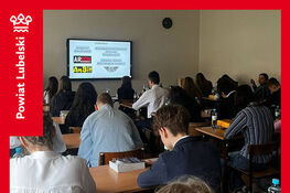 Na zdjęciu widzimy uczestników siedzących w klasie, skierowanych w stronę ekranu projekcyjnego. Na ścianie widnieje slajd z nazwami sponsorów. To finał konkursu translatorskiego „Skrzydlate Słowa”.