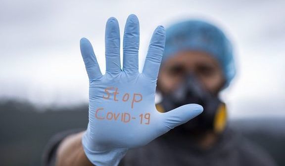 mężczyzna w masce i rękawiczkach, na rękawiczce napis "stop COVID-19"