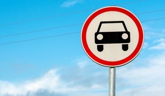 Znak drogowy zakazu wjazdu dla pojazdów na niebieskim niebie z chmurami.