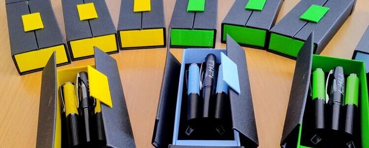 Zestaw długopisów i pióro, tło herby Powiatu Puławskiego