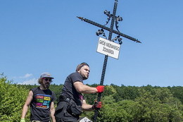 Osoba trzymająca krzyż z tabliczka Grób nieznanego żołnierza