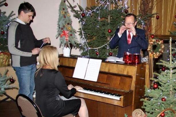 Osoba przy pianinie i dwóch mężczyzn śpiewających
