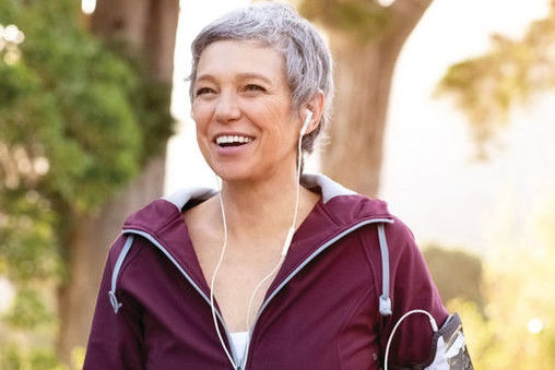 Zdjęcie uśmiechniętej kobiety ze słuchawkami w parku