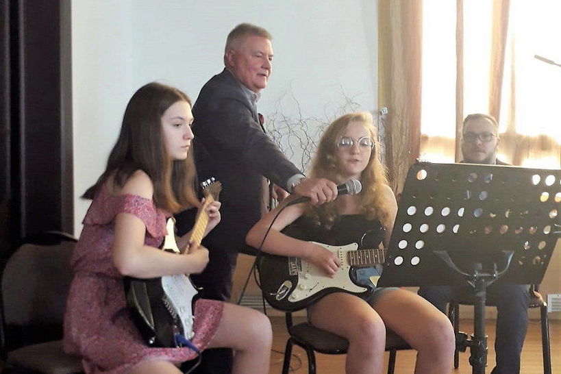 Zdjęcie z występu, dwie dziewczyny grające na gitarach, jedna z nich śpiewa
