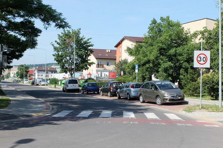 Na zdjęciu ulica z zaparkowanymi samochodami