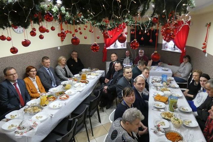 Na zdjęciu osoby uczestniczące w spotkaniu przy zastawionych jedzeniem stołami