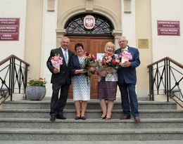 Jubileusz Złotych godów dwie pary z kwiatami na schodach przed budynkiem