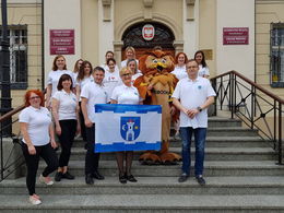 Zdjęcie grupowe na schodach przed urzędem - Jedna osoba trzyma flagę