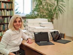 Dyrektor Zespołu Szkół Magdalena Pawiłojć siedzi przy biurku, na którym leżą otrzymane pakiety multimedialne.