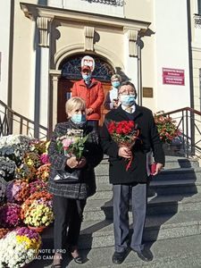 Na zdjęciu widać parę z bukietem kwiatów, w tle Ratusz Miejski 