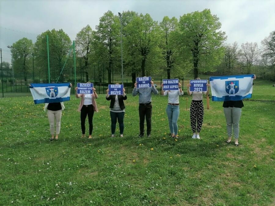 Na zdjęciu stoi siedem osób trzymających przed sobą flagi Świebodzic oraz kartki z napisami biało-niebieskimi