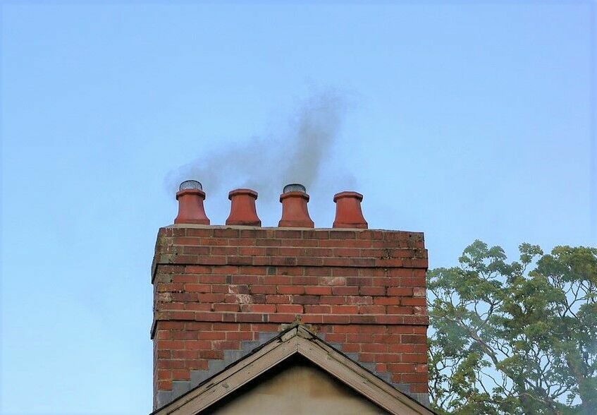 Na zdjęciu widoczny jest komin z którego wydobywa się czarny dym.