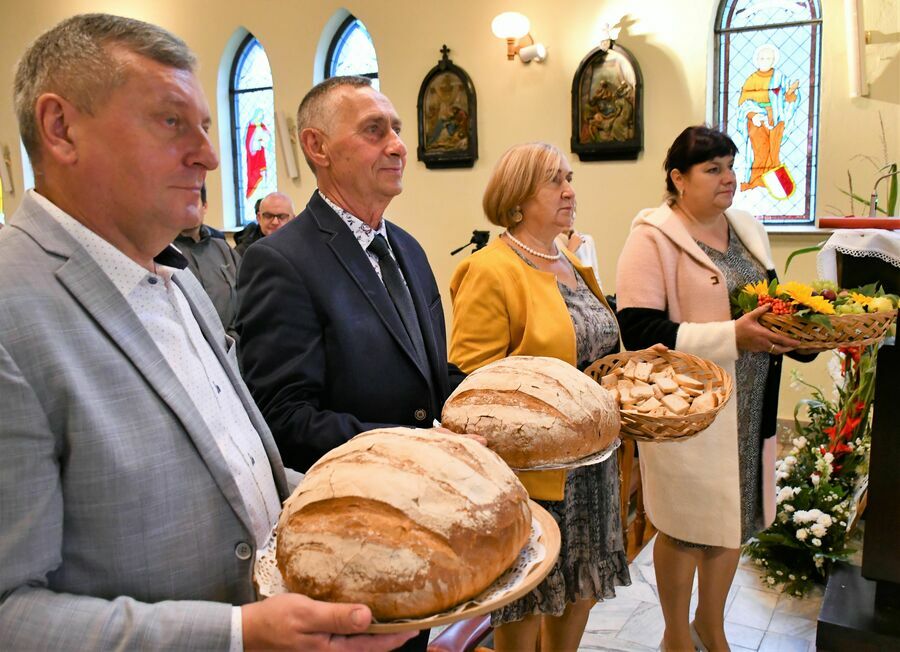 Na zdjęciu widoczni są rolnicy stojący z bochenkami chleba 