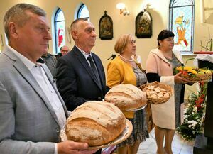 Na zdjęciu widoczni są rolnicy stojący z bochenkami chleba 