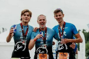 Na zdjęciu widoczni są trzej mężczyźni z medalami na szyjach w niebieskich koszulkach z krótkim rękawem.