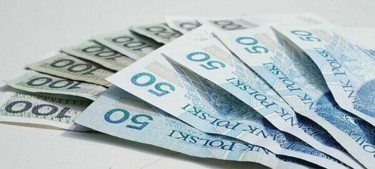 Zdjęcie przedstawia rozłożone banknoty o nominałach 50 i 100 złotych na jasnym tle.