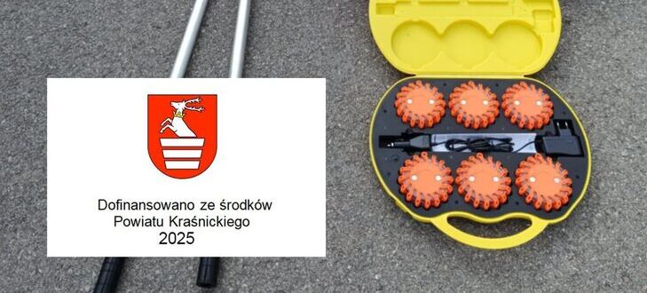 Na asfalcie ułożono sprzęt ratowniczy: łopaty, czerwone węże strażackie, lampy sygnalizacyjne w żółtej walizce i inne akcesoria. Obok jest logo z herbem i napisem "Dofinansowano ze środków Powiatu Kraśnickiego 2025".