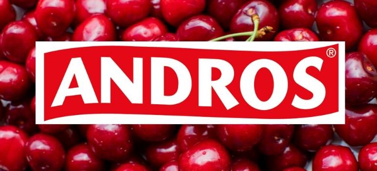 Czerwone wiśnie w dużej ilości, częściowo przykryte logo marki "Andros" na białym tle.