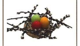 Gniazdo z gałązkami i pąkami wierzby z trzema kolorowymi jajkami w środku, symbolizującymi Wielkanoc.