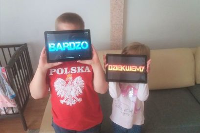 Dwójka dzieci z tabletami. Na tabletach wyświetlone napisy BARDZO DZIĘKUJEMY