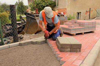 Pracownik układający kostkę betonową podczas remontu chodnika w Wierzbnej.