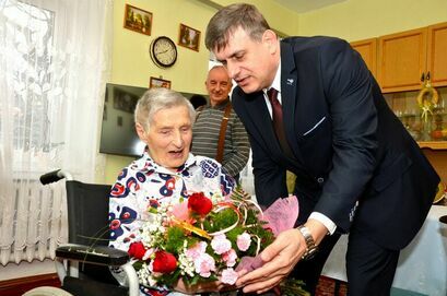 Burmistrz Leszek Michalak wręcza kwiaty jubilatce