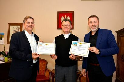 Burmistrz Leszek Michalak, zastępca burmistrza Przemysław Sikora i ksiądz Mariusz Walas trzymają promesy
