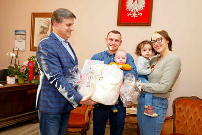 Burmistrz Leszek Michalak wręcza rodzinie pakiet powitalny w ramach akcji "Paka dla Niemowlaka"