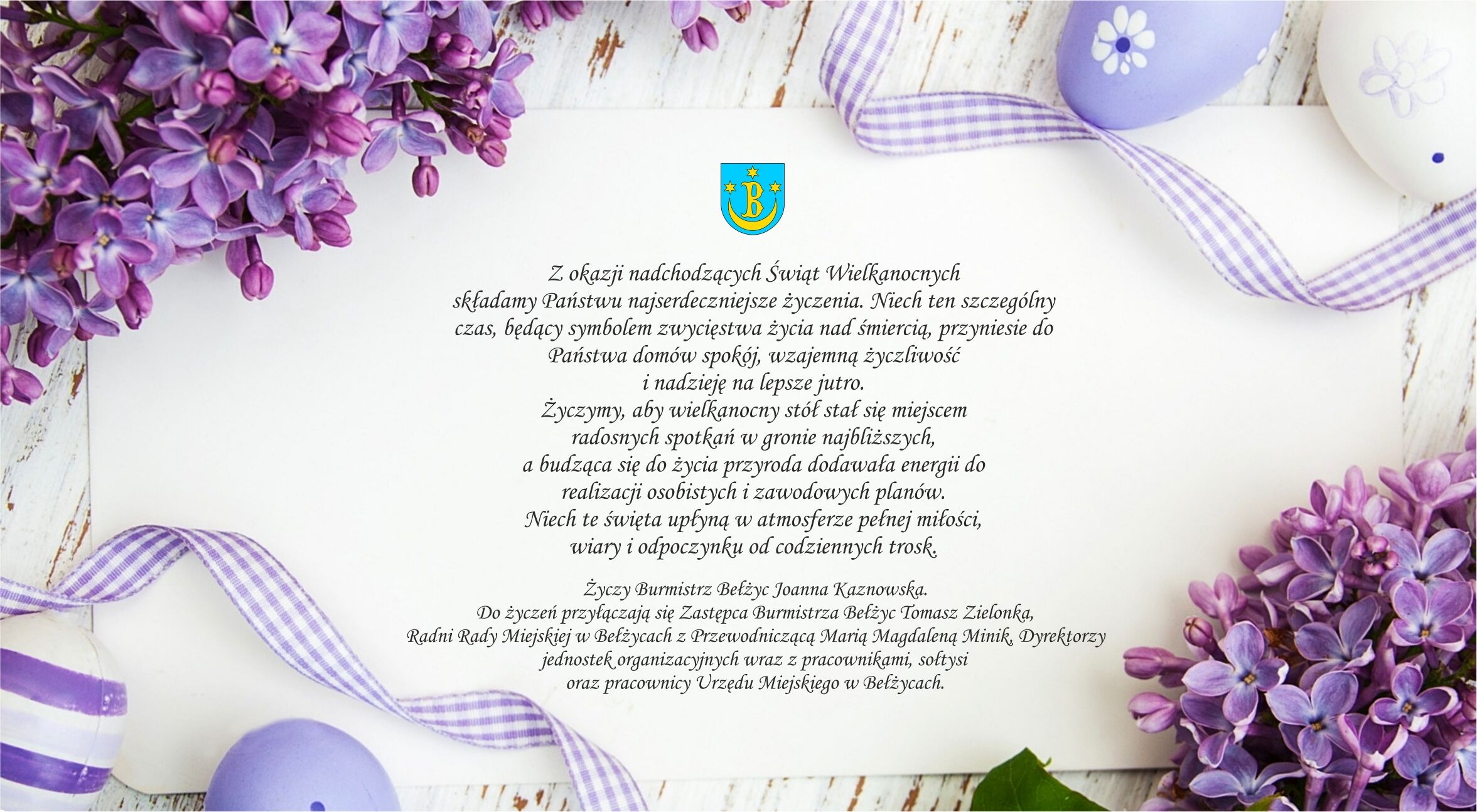 Wielkanocna karta z życzeniami od władz Bełżyc. Na jasnym, drewnianym tle leży biała karta otoczona gałązkami fioletowego bzu, pisankami w odcieniach fioletu oraz ozdobną wstążką w fioletową kratkę. W górnej części karty widnieje herb Bełżyc. Treść życzeń: „Z okazji nadchodzących Świąt Wielkanocnych składamy Państwu najserdeczniejsze życzenia. Niech ten szczególny czas, będący symbolem zwycięstwa życia nad śmiercią, przyniesie do Państwa domów spokój, wzajemną życzliwość i nadzieję na lepsze jut