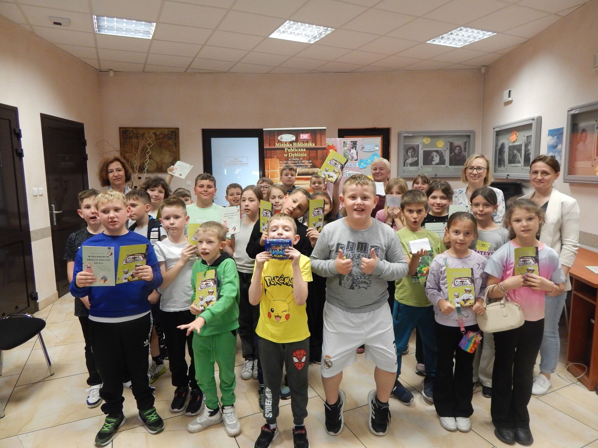 zdjęcie przedstawia grupę uczniów stojących na tle banneru biblioteki i planszy z napisem spotkanie autorskie