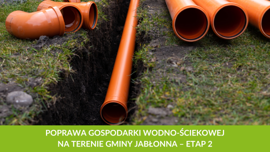 Prace instalacyjne – duże, pomarańczowe rury kanalizacyjne leżące obok wykopanego rowu, z tekstem mówiącym o poprawie gospodarki wodno-ściekowej w gminie Jabłonna, etap 2.