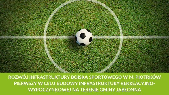 Piłka nożna na środku zielonego boiska z wyraźnym białym okręgiem w centrum. Tekst dotyczący rozwoju infrastruktury sportowej.