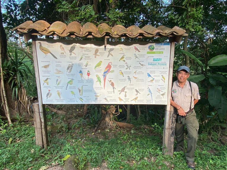 Yobani przy tablicy z gatunkami ptaków jego autorstwa.