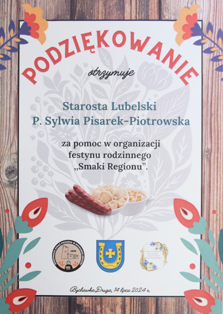 Plakat z podziękowaniami na drewnianym tle, z grafiką kwiatów i herbów, z tekstem w języku polskim doceniającym pomoc P. Sylwii Pisarek-Piotrowskiej.