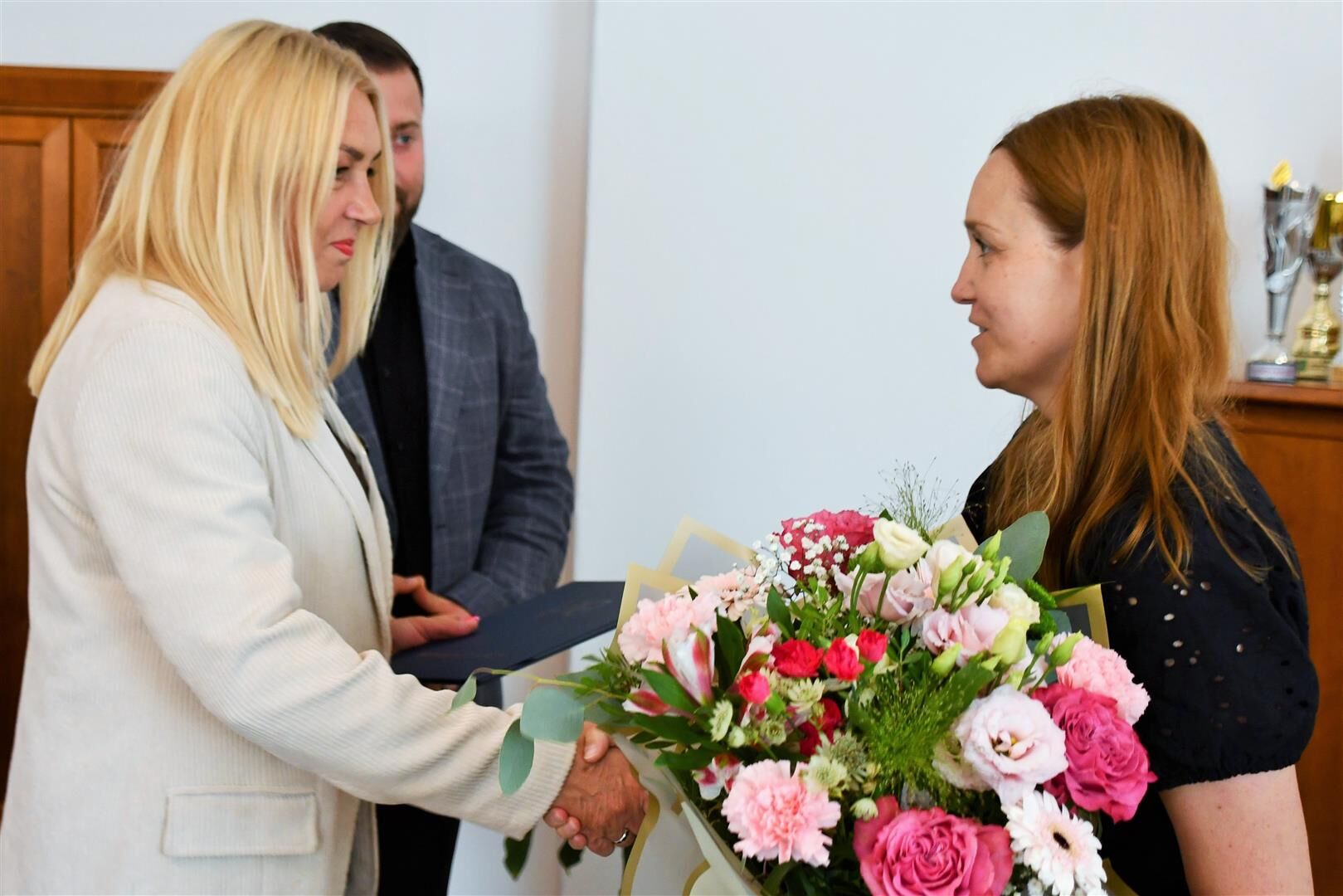 Starosta Teresa Gutowska i członek zarządu Łukasz Skowyra składają gratulacje oraz podają bukiet kwiat&oacute;w dyrektor Katarzynie Adamowskiej-Kane