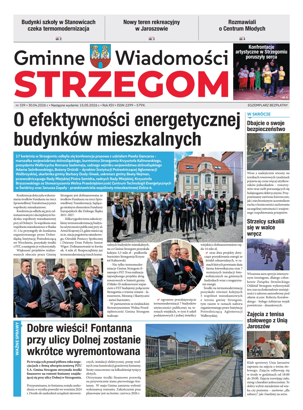 Na okładce "Gminne Wiadomości Strzegom" znajduje się artykuł o efektywności energetycznej budynków. Obraz przedstawia grupę ludzi oraz budynki w tle. Innym tematem jest fontanna w Dolnej oraz kwestie bezpieczeństwa.