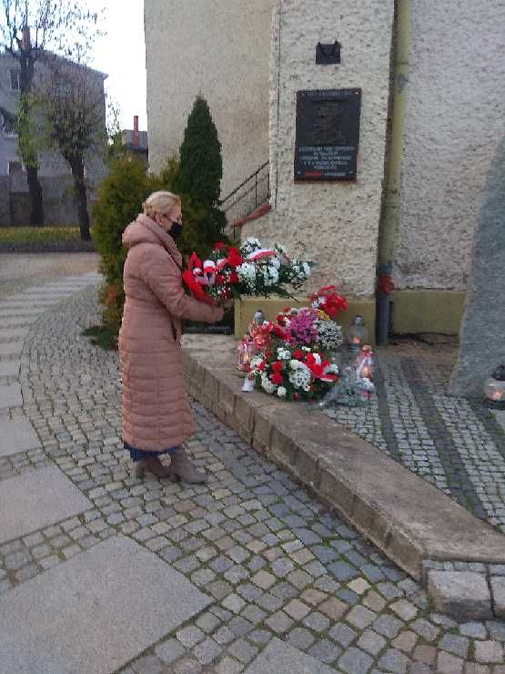 Kobieta składająca kwiaty pod tablicą pamiątkową