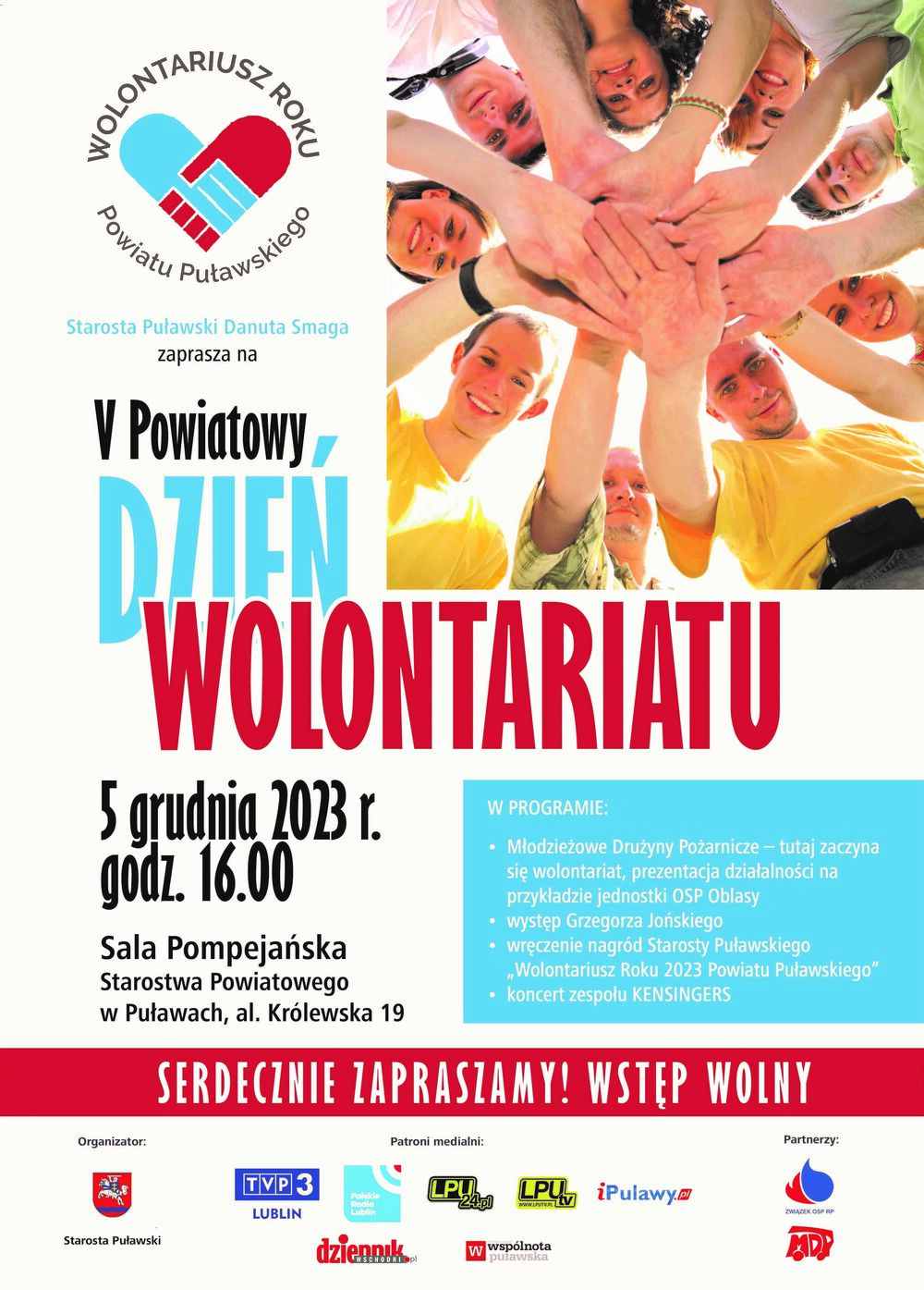Plakat promujący "Dzień Wolontariusza" z datą i godziną w centralnej części, otoczony zdjęciem uśmiechniętych ludzi trzymających się za ręce, utworzonych w kształt serca.