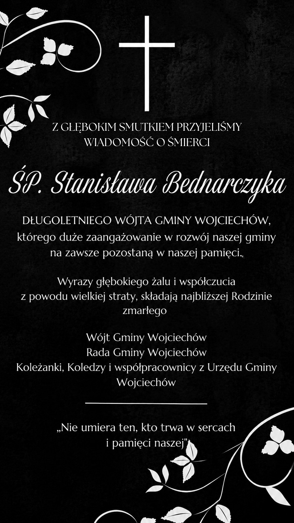 Czarna klepsydra pogrzebowa z krzyżem i wzorem kwiatowym. Zawiera informacje o śmierci Stanisława Bednarzyka, byłego w&oacute;jta gminy Wojciech&oacute;w. Wyrazy wsp&oacute;łczucia dla rodziny i wspomnienie jego wkładu w rozw&oacute;j gminy.